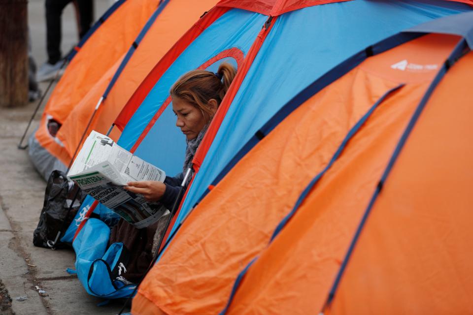 A woman reads a newspaper inside her tent as migrants camp out on the street outside an overflowing sports complex on Nov. 28, 2018, where more than 5,000 Central American migrants are sheltering in Tijuana, Mexico.