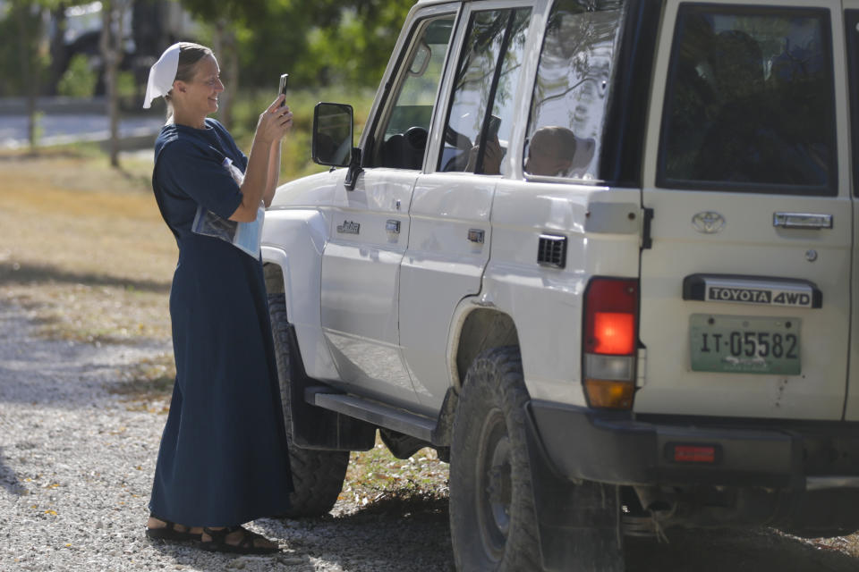 A woman takes a photo of members of the Christian Aid Ministries who are departing to the airport from the group's headquarter at Titanyen, north of Port-au-Prince, Haiti, Thursday, Dec. 16, 2021. Twelve remaining members of a U.S.-based missionary group who were kidnapped two months ago have been freed, according to the group and to Haitian police. (AP Photo/Odelyn Joseph)