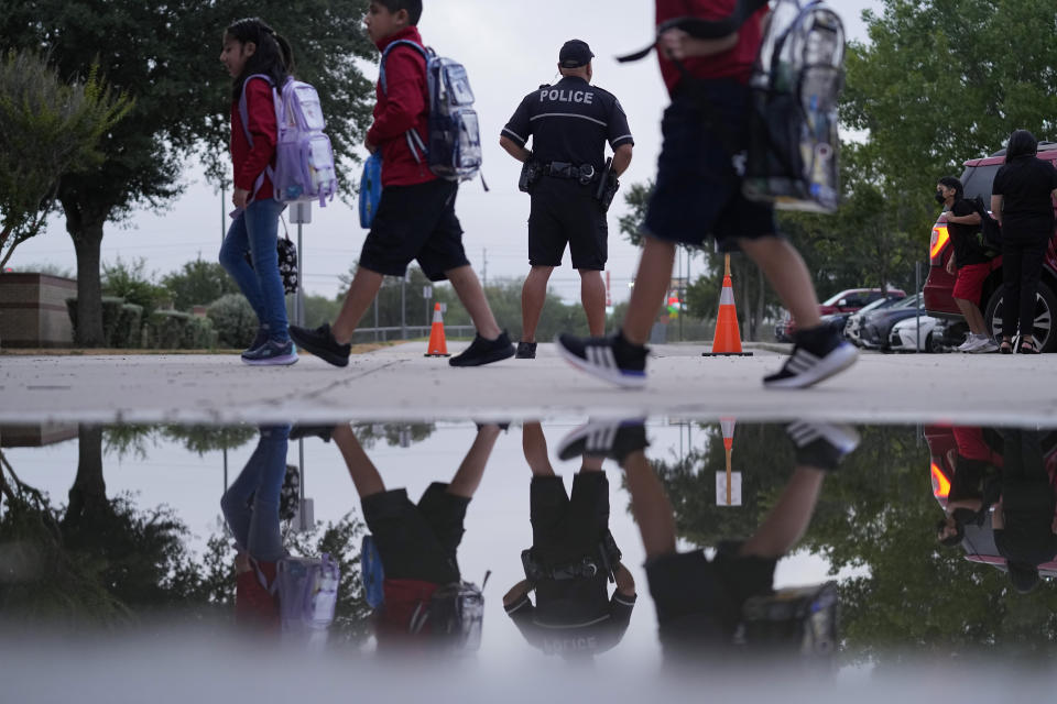 Southside Independent School District police officer Ruben Cardenas, center, keeps watch as students arrive at Freedom Elementary School, Wednesday, Aug. 23, 2023, in San Antonio. Most Texas school districts say they are unable to comply with a new law requiring armed officers on every campus. The mandate was one of Republican lawmakers' biggest acts following the Uvalde school shooting in 2022 that killed 19 children and two teachers. (AP Photo/Eric Gay)