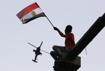 A man waves an Egyptian national flag as a military helicopter circles over Tahrir Square, after the swearing-in ceremony of president elect Abdel Fattah al-Sissi, in Cairo, June 8, 2014. REUTERS/Mohamed Abd El Ghany