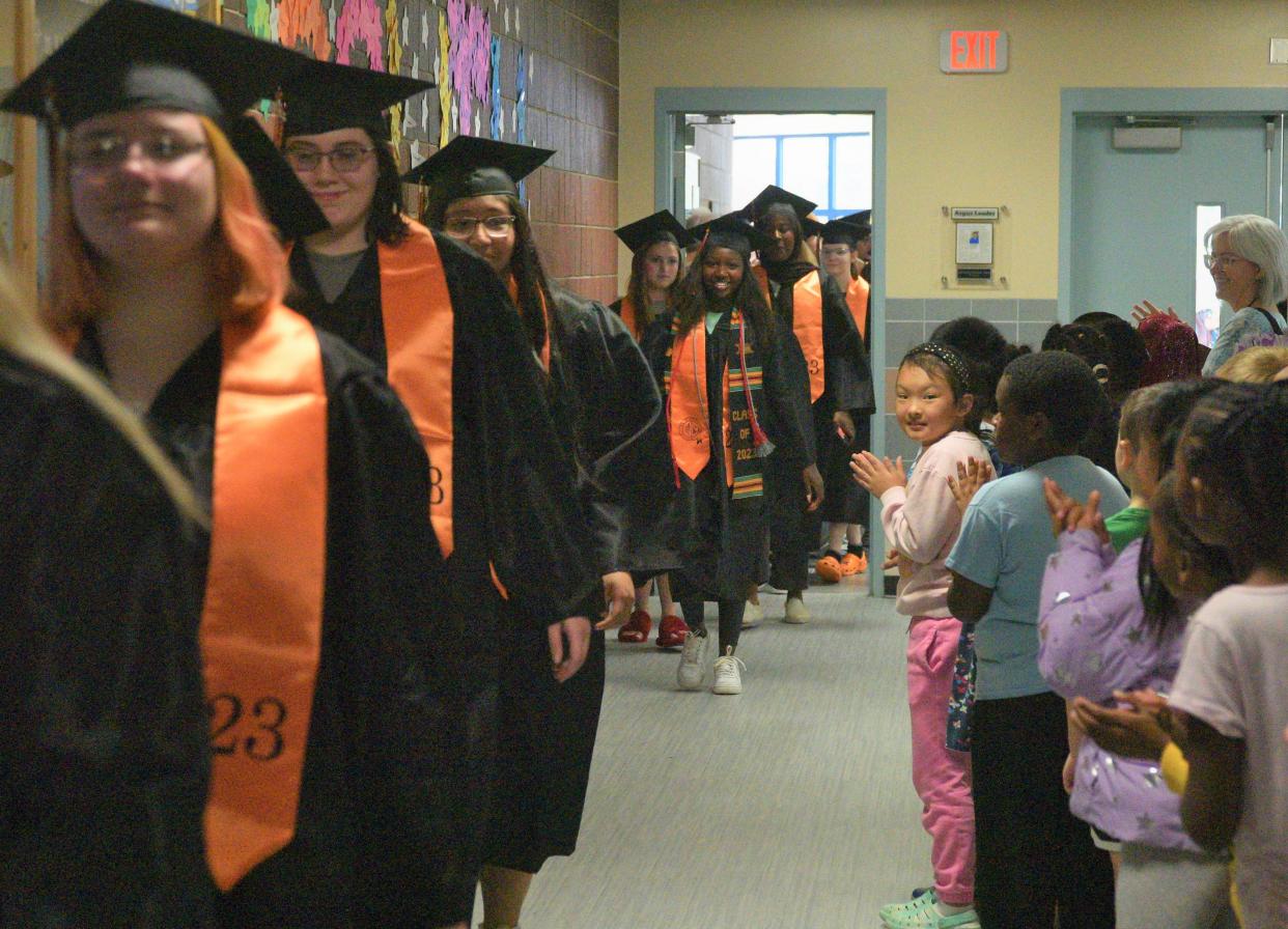 Seniors from the Washington High School Class of 2023 (left) stroll through the halls of Anne Sullivan Elementary School on Tuesday, May 16, 2023 as their former teachers and youngest peers (right) applaud them.