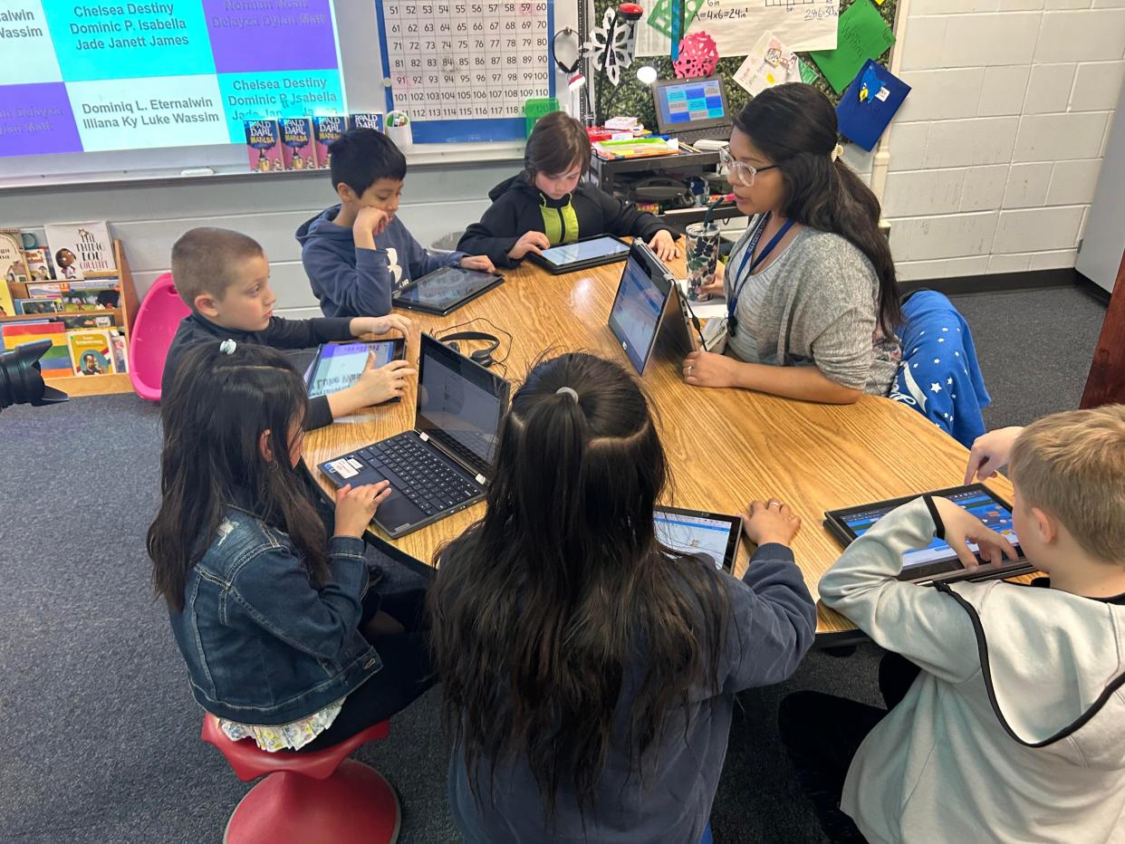 Third grade teacher Daisy Diaz works with Perry Elementary students on computer science.