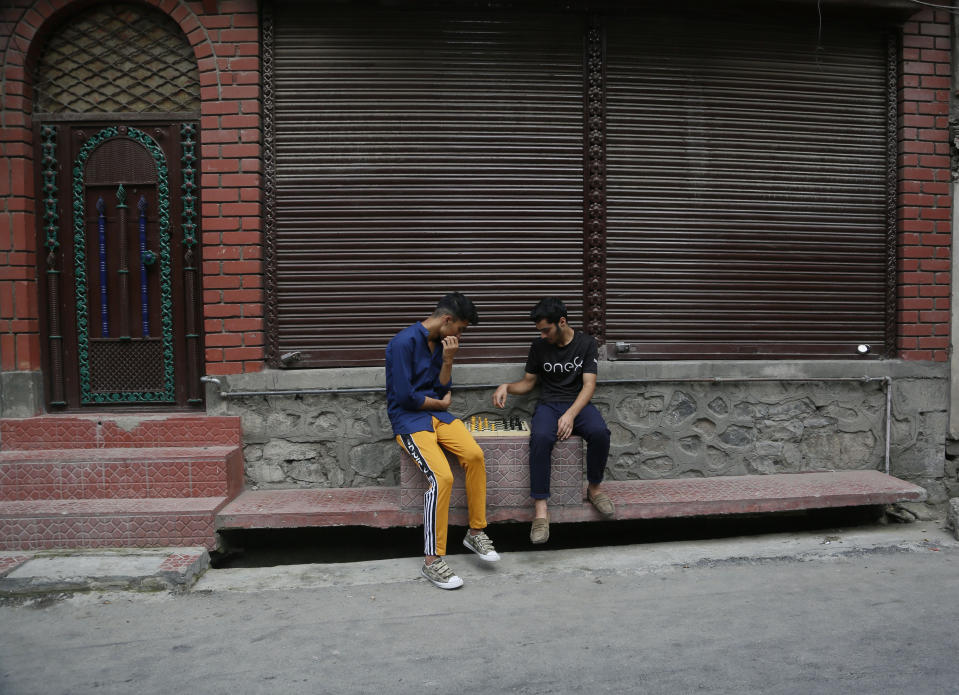 Kashmiri boys play chess at a closed market in Srinagar, Indian controlled Kashmir, Wednesday, Aug. 28, 2019. India's government, led by the Hindu nationalist Bharatiya Janata Party, imposed a security lockdown and communications blackout in Muslim-majority Kashmir to avoid a violent reaction to the Aug. 5 decision to downgrade the region's autonomy. The restrictions have been eased slowly, with some businesses reopening, some landline phone service restored and some grade schools holding classes again, though student and teacher attendance has been sparse. (AP Photo/Mukhtar Khan)