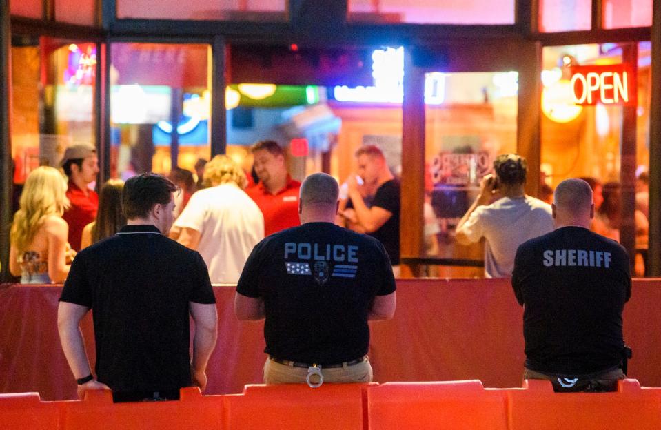 Police officers stand outside Brothers Bar & Grill on April 23, 2022, after four men were injured in shootings in downtown Bloomington over Little 500 weekend.