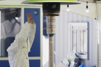 A medical worker wearing protective gear warms her hands in the sub-zero temperatures at a coronavirus testing site in Seoul, South Korea, Sunday, Dec. 20, 2020. (AP Photo/Lee Jin-man)