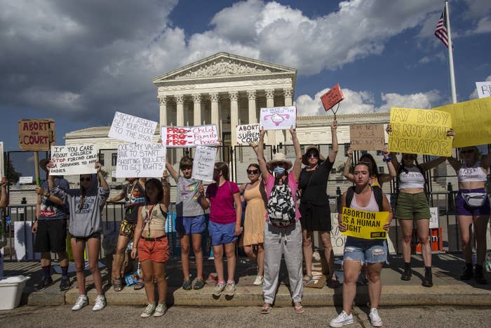 People standing outside the Supreme Court holding signs, including "Abortion is a human right"