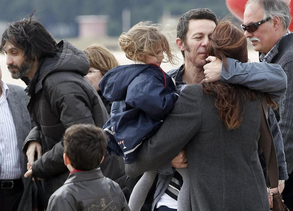 Spanish reporter Javier Espinosa, second right, holds his daughter Nur as he is greeted by his wife Monica Garcia upon his arrival at the military airport of Torrejon in Madrid, Spain, Sunday, March 30, 2014. Two Spanish journalists who were freed after being kidnapped for more than six months in Syria by a rogue al-Qaida group are flying back home Sunday, Spain’s Defense Ministry said. The El Mundo newspaper reported earlier that its war correspondent Javier Espinosa made contact late Saturday from Turkey, where he and photographer Ricardo Garcia Vilanova were under military protection. (AP Photo/Paco Campos, Pool)