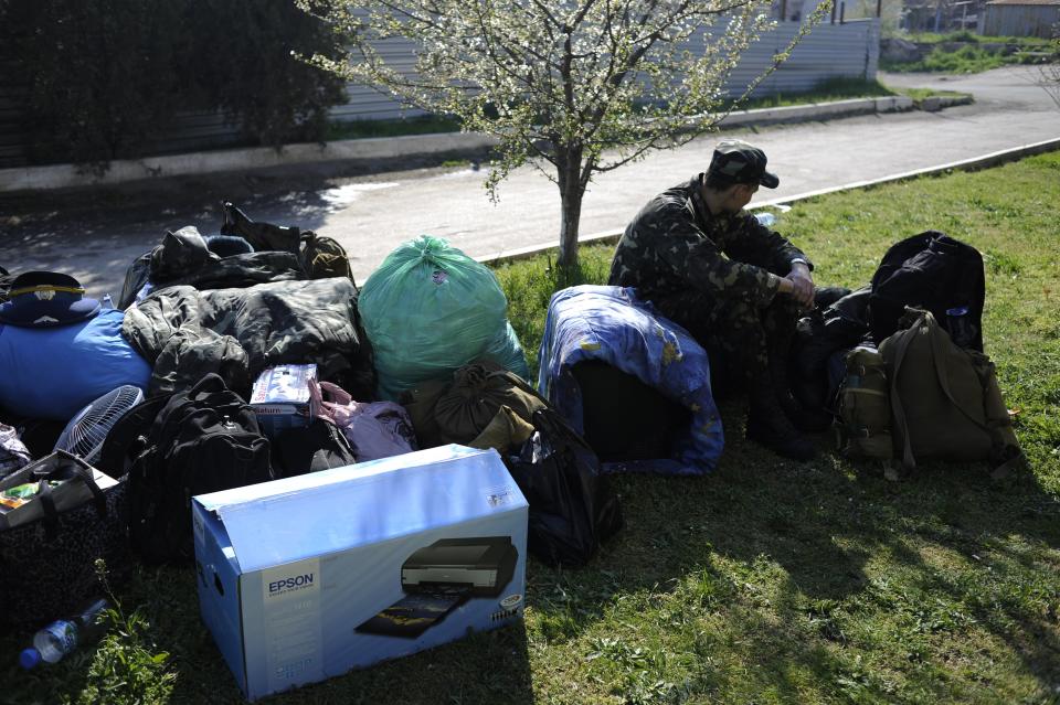 A Ukrainian serviceman sits next to packed things before leaving the Belbek airbase near Sevastopol, Crimea, Friday, March 28, 2014. Ukraine started withdrawing its troops and weapons from Crimea, now controlled by Russia. Russia's president says Ukraine could regain some arms and equipment of military units in Crimea that did not switch their loyalty to Russia. (AP Photo/Andrew Lubimov)