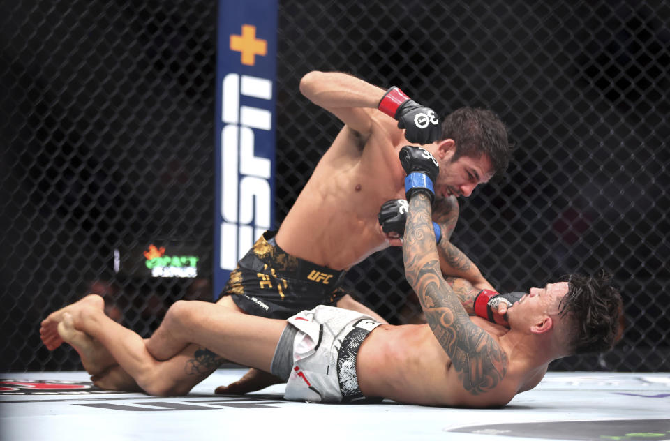 UFC flyweight champion Alexander Pantoja, top, punches Brandon Royval during the UFC 296 mixed martial arts event Saturday, Dec. 16, 2023, in Las Vegas. Pantoja retained his title by unanimous decision. (Steve Marcus/Las Vegas Sun via AP)