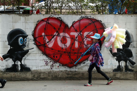 A woman walk past a graffiti with the word 'vote', as the first national election since the military seized power in 2014 coup is set for next month, in Bangkok, Thailand January 11, 2019. REUTERS/Jorge Silva