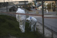 Greek forensic experts search at the scene after a powerful bomb exploded outside private Greek television station Skai, in Faliro, Athens, Monday, Dec, 17, 2018. Police said the blast occurred outside the broadcasters' headquarters near Athens after telephoned warnings prompted authorities to evacuate the building, causing extensive damage but no injuries. (AP Photo/Petros Giannakouris)