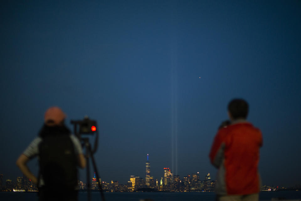 People try to take pictures of the Tribute in Light as it rises above the lower Manhattan skyline, Wednesday, Sept. 11, 2019 in Bayonne, N.J. (AP Photo/Eduardo Munoz Alvarez)