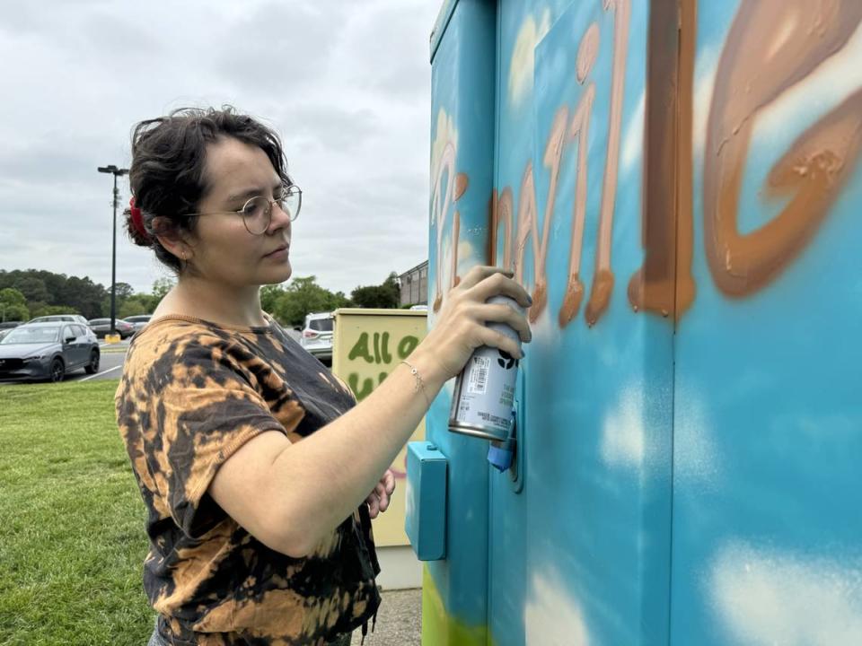 Art student Ana Garay painting a utility box at Pineville Lake Park.