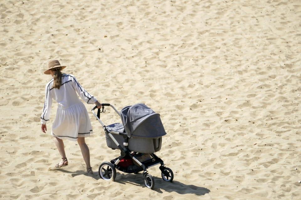A woman pulls a pushchair across the beach in Bournemouth (Steve Parsons/PA) (PA Wire)