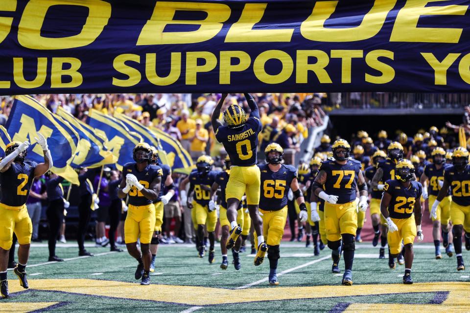 Michigan defensive back Mike Sainristil jumps up to touch the banner as the team takes the field before U-M's 30-3 win on Saturday, Sept. 2, 2023, at Michigan Stadium.