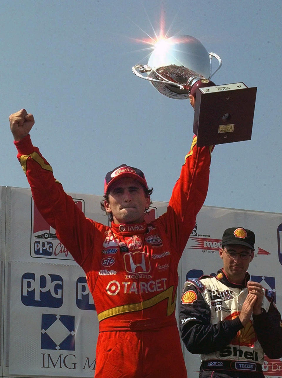 FILE - In this July 13, 1997, file photo, Alex Zanardi hoists his trophy after winning the Grand Prix of Cleveland, as third placed Brian Herta looks on at right. Every now and then Alex Zanardi has a chance encounter with someone who reminds him there’s never any reason to feel sorry for himself, not that he ever had during his two vastly different lifetimes: the one with legs, and the other as a double-amputee. (AP Photo/Amy Sancetta, File)
