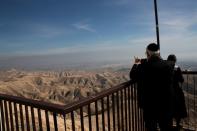 The Palestinian city of Jericho is seen in the background as a Jewish man takes a photograph from a lookout point near the Israeli settlement of Mitzpe Yericho in the Jordan Valley in the Israeli-occupied West Bank