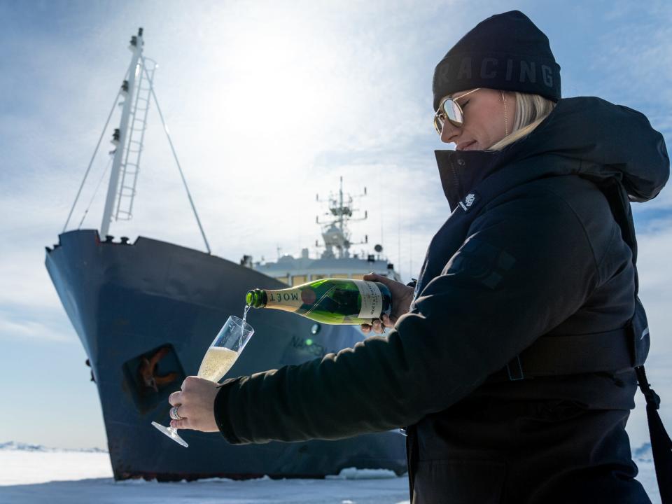 A person pouring a drink near a ship