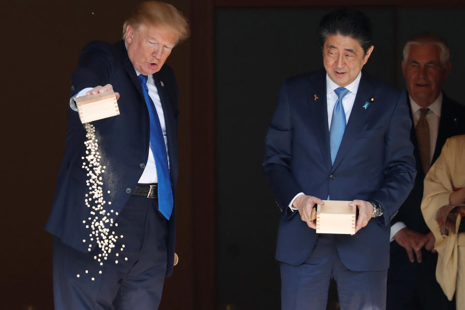 President Donald Trump pours fish food out as Japan's Prime Minister Shinzo Abe looks on while they were feeding carps before their working lunch at Akasaka Palace in Tokyo.