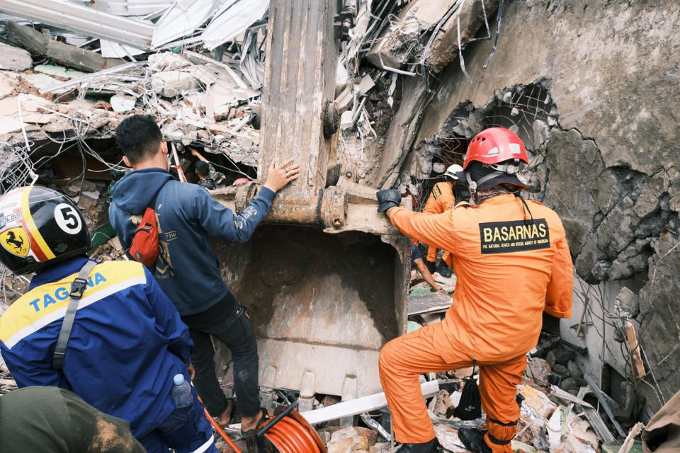 Rescuers search for victims at the ruin of a building damaged by an earthquake in Mamuju, West Sulawesi, Indonesia, Saturday, Jan. 16, 2021. Damaged roads and bridges, power blackouts and lack of heavy equipment on Saturday hampered Indonesia's rescuers after a strong and shallow earthquake left a number of people dead and injured on Sulawesi island. (AP Photo/Sadly Ashari Said)