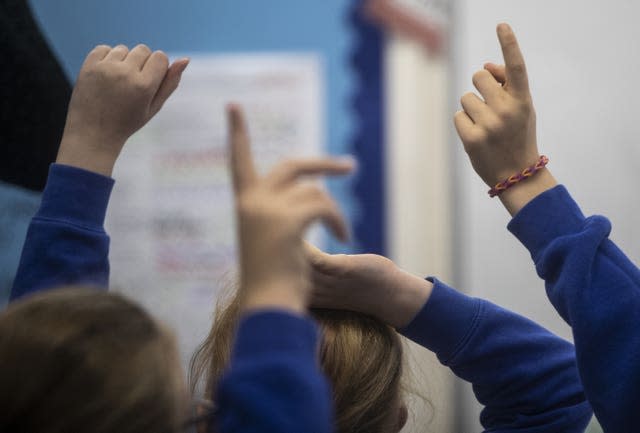 Close-up of schoolchildren's hands raised in a classroom