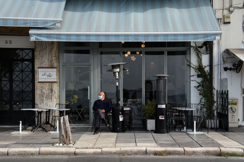 A man sits outside a closed cafe, amid the coronavirus disease (COVID-19) pandemic, in Thessaloniki