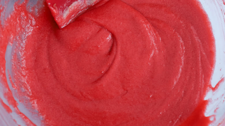 red batter in bowl with rubber spatula