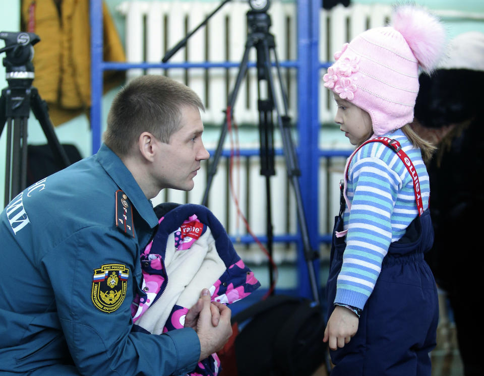 An Emergency Situations employee speaks to girl in a evacuation center near a collapsed section of an apartment building in Magnitogorsk, a city of 400,000 people, about 1,400 kilometers (870 miles) southeast of Moscow, Russia, Wednesday, Jan. 2, 2019. Russian emergency officials say the death toll from the partial collapse of an apartment building has risen to over 25 after more bodies were recovered from the rubble. The grim discovery on Wednesday afternoon left 15 residents of the 10-story building in the Russian city of Magnitogorsk still unaccounted for. (AP Photo/Maxim Shmakov)