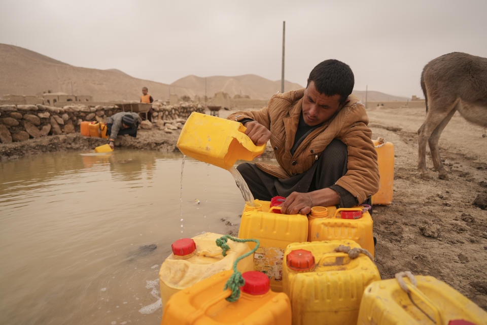 Afghan man fills oil canisters with water near the improvised dam, in Hachka, Afghanistan, Monday, Dec. 13, 2021. Severe drought has dramatically worsened the already desperate situation in Afghanistan forcing thousands of people to flee their homes and live in extreme poverty. Experts predict climate change is making such events even more severe and frequent. (AP Photo/Mstyslav Chernov)