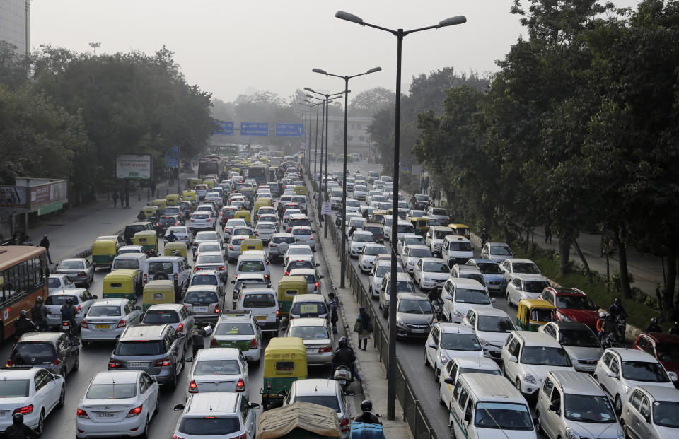 FILE- In this Jan. 16, 2016, file photo, vehicles move slowly through a traffic intersection after the end of a two-week experiment to reduce the number of cars to fight pollution in in New Delhi, India. India is grappling with two public health emergencies: critically polluted air and the pandemic. Nowhere is this dual threat more pronounced than in the Indian capital New Delhi, where the spike in winter pollution levels has coincided with a surge of COVID-19 cases. (AP Photo/Altaf Qadri, File)