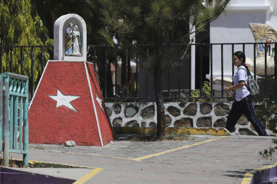 Una niña salvadoreña pasa junto a un altar religioso pintado con los colores del Frente Farabundo Martí para la Liberación Nacional (FMLN) ante una iglesia en San José Las Flores, El Salvador, el miércoles28 de febrero de 2024. El Salvador celebró sus elecciones municipales el 3 de marzo. (AP Foto/Salvador Meléndez)