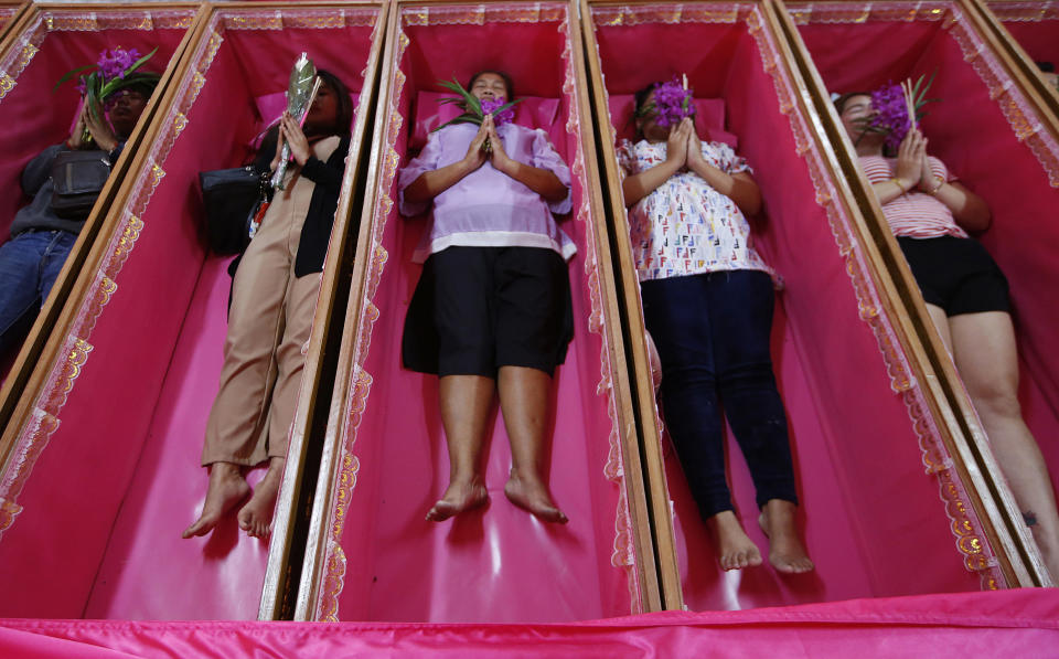 Worshippers pray as they take turns lying in coffins during a ceremony at the Takien temple in suburban Bangkok, Thailand Monday, Dec. 31, 2018. Worshippers believe that the ceremony – symbolizing death and rebirth – helps them rid themselves of bad luck and are born again for a fresh start in the new year. (AP Photo/Sakchai lalit)