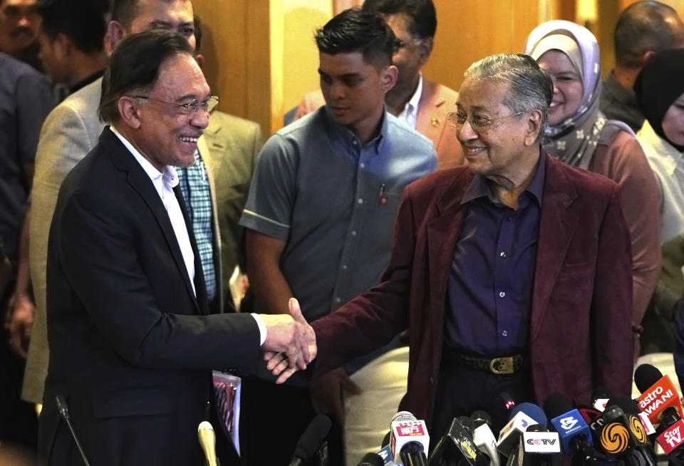 Malaysian Prime Minister Mahathir Mohamad, right, shakes hands with successor Anwar Ibrahim in Putrajaya, Malaysia on Feb. 22, 2020. With a battle cry of “We Can,” reformist opposition leader Anwar Ibrahim has launched what could be his last chance to fulfill a 2-decade-long quest to become Malaysia’s leader in Nov. 19, 2022 general elections. (AP Photo/Vincent Thian)