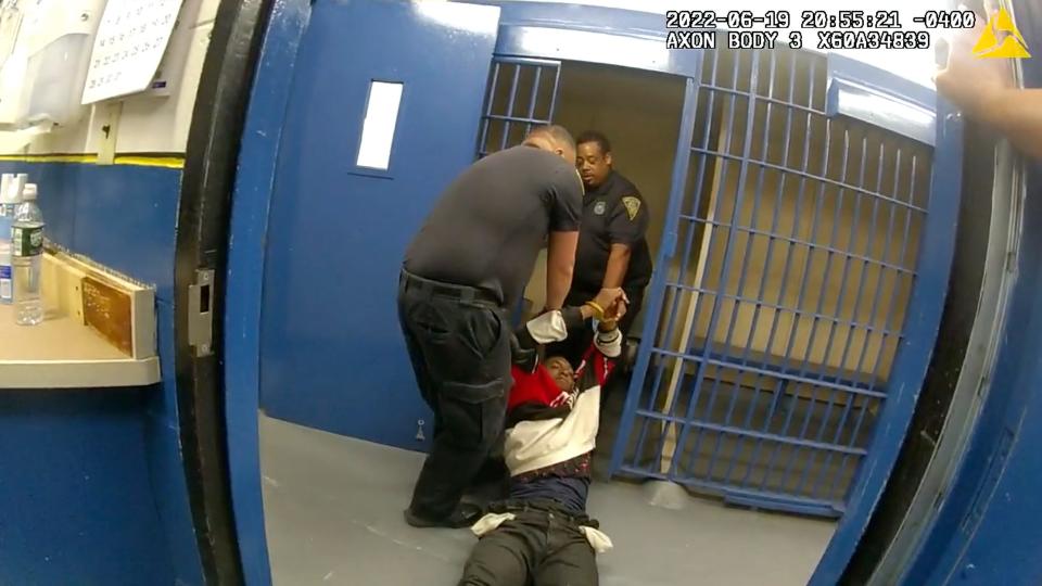 In this frame taken from police body camera video, Richard Cox, center, is dragged into a cell after being pulled from the back of a police van after being detained by New Haven Police, June 19, 2022, in New Haven, Conn. Officials in Connecticut said, Wednesday, June 22, 2022, that two New Haven officers have been placed on paid leave and three others were reassigned after Cox was seriously injured in the back of a police van. (New Haven Police via AP)