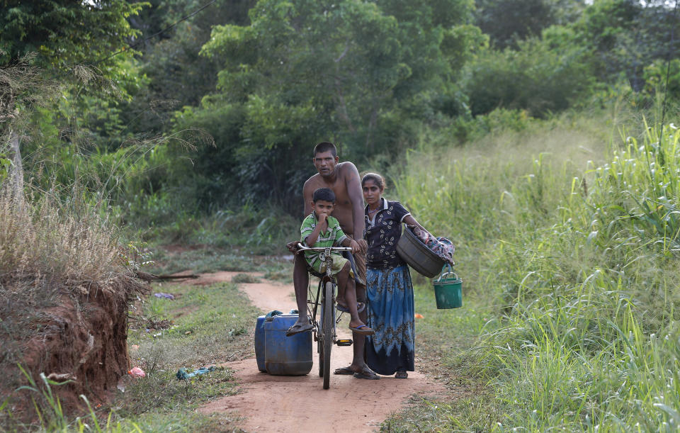 A Sri Lankan Telugu family travels to collect water for their household consumption in Nachchikulama, Sri Lanka, Monday, June 8, 2020. Sri Lanka's Telugu community, whose nomadic lifestyle has increasingly clashed with the modern world, is facing another threat that could hasten its decline: the COVID-19 pandemic. (AP Photo/Eranga Jayawardena)