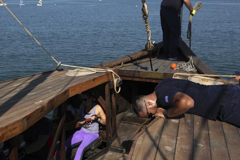 In this Sunday, Sept. 16, 2018 photo, visitors row the Olympias, a replica of an ancient galley, as a Greek Navy sailor gives instructions at Saronic gulf in southern Athens. The 37-meter (121-foot) wooden vessel moored off southern Athens is an experimental reconstruction of the trireme, the sleek ancient Greek warship that halted a Persian invasion of Europe and ruled the Mediterranean for centuries. Every summer, visitors can get a whiff of life in the galleys 2,500 years ago by joining the crew of the Olympias _ and work up a sweat rowing it. (AP Photo/Thanassis Stavrakis)