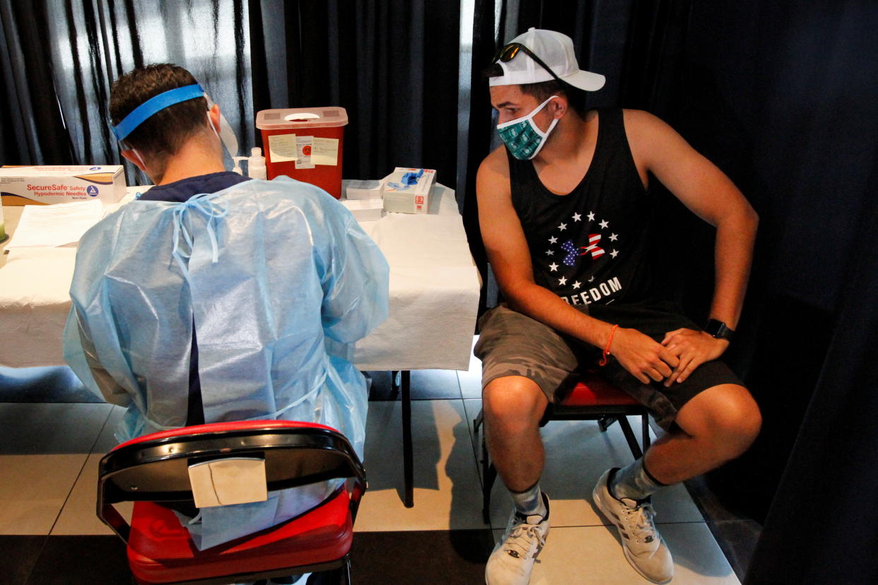 A man talks with a health worker as he waits to be inoculated against the coronavirus disease (COVID-19) during a vaccination event hosted by Miami-Dade County and Miami Heat, at FTX Arena in Miami, Florida, U.S., August 5, 2021. REUTERS/Marco Bello