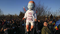 Anti-vaccination protesters hold a doll with "I don't want to be a lab rat" written on it during a rally outside the parliament building in Bucharest, Romania, Sunday, March 7, 2021. Some thousands of anti-vaccination protestors from across Romania converged outside the parliament building protesting against government pandemic control measures as authorities announced new restrictions amid a rise of COVID-19 infections. (AP Photo/Vadim Ghirda)