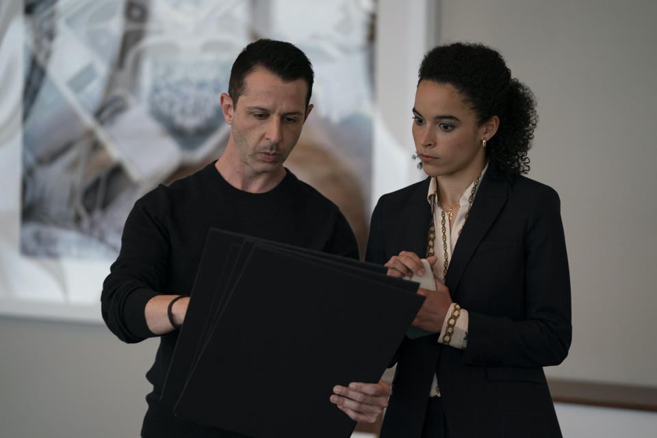 Two individuals examining a document together, one holding it, office setting