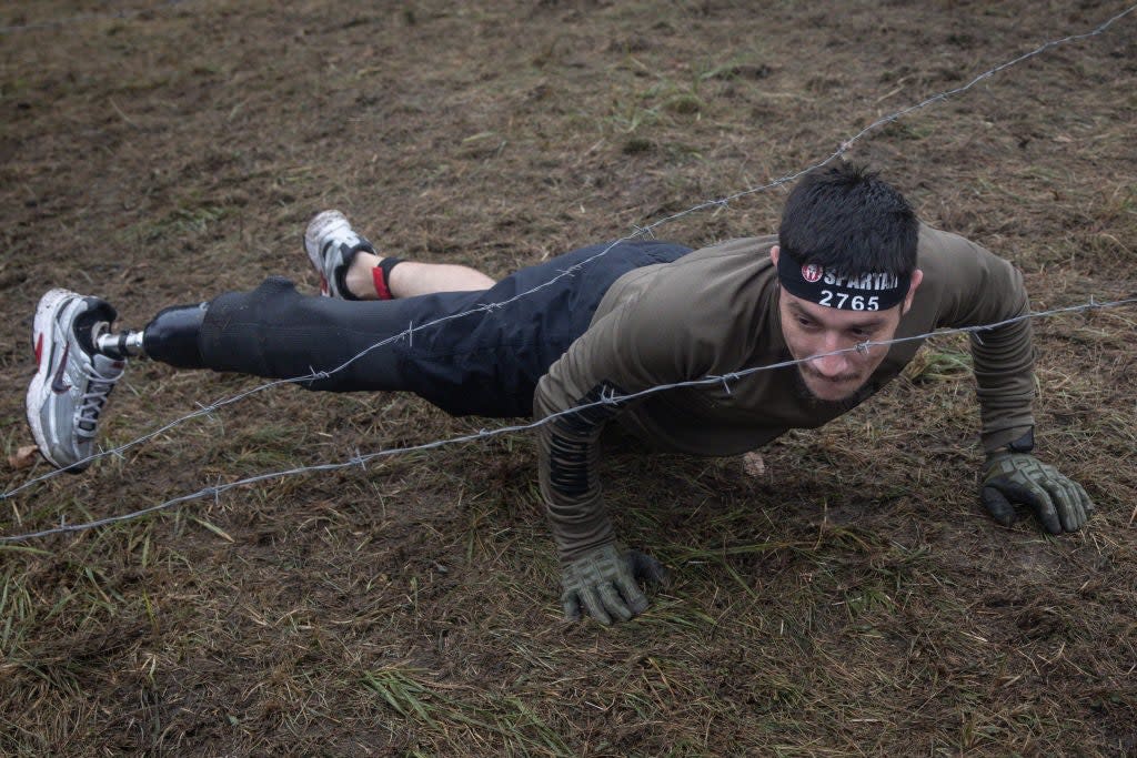 25 year-old amputee soldier Oleksander crawls under a barbed-wire obstacle during a Spartan race in Kyiv. The a 92nd Brigade sniper lost his leg while evacuating injured members of his team when they were hit by helicopter and artillery fire (Getty Images)