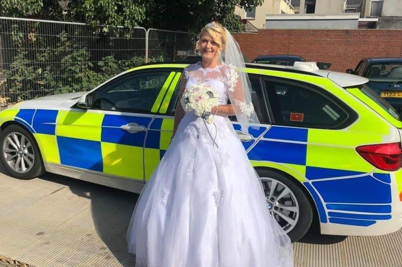 Bride standing next to a police car