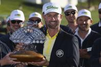 Webb Simpson holds the champion's trophy and wears the winner's jacket as he stands with the Thunderbirds Charities members after the final round of the Waste Management Phoenix Open PGA Tour golf event Sunday, Feb. 2, 2020, in Scottsdale, Ariz. (AP Photo/Ross D. Franklin)