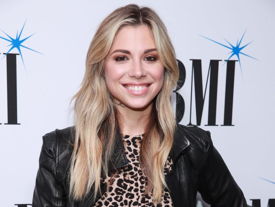 Christina Perri is posing at 67th Annual BMI Pop Awards in a cheetah dress and leather jacket.