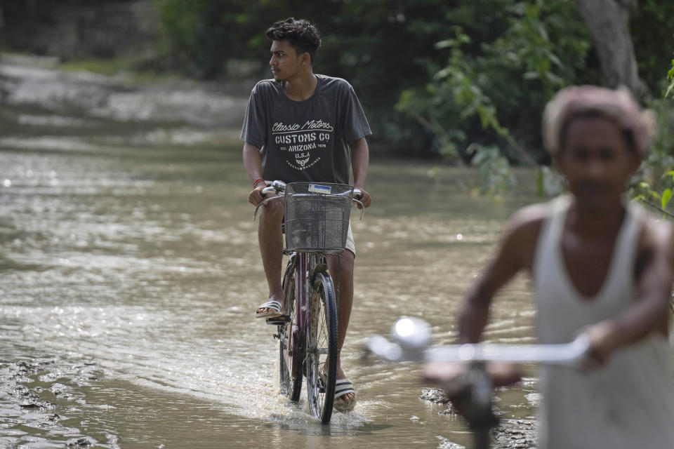 A villager rides his cycle past floodwaters in Bali village, west of Guwahati, India, Friday, June 23, 2023. Tens of thousands of people have moved to relief camps with one person swept to death by flood waters caused by heavy monsoon rains battering swathes of villages in India’s remote northeast this week, a government relief agency said on Friday. (AP Photo/Anupam Nath)