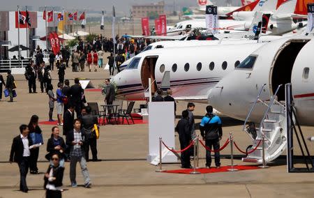 Guests walk next to aircraft during the Asian Business Aviation Conference and Exhibition (ABACE) at Hongqiao International Airport in Shanghai in this April 15, 2014 file photograph. REUTERS/Carlos Barria/Files