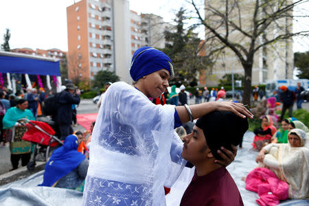 FILE PHOTO: A young Sikh helps his friend to put on his turban as they join celebrations at the Vaisakhi Festival, marking the New Year, in Rome, Italy April 14, 2019. REUTERS/Yara Nardi