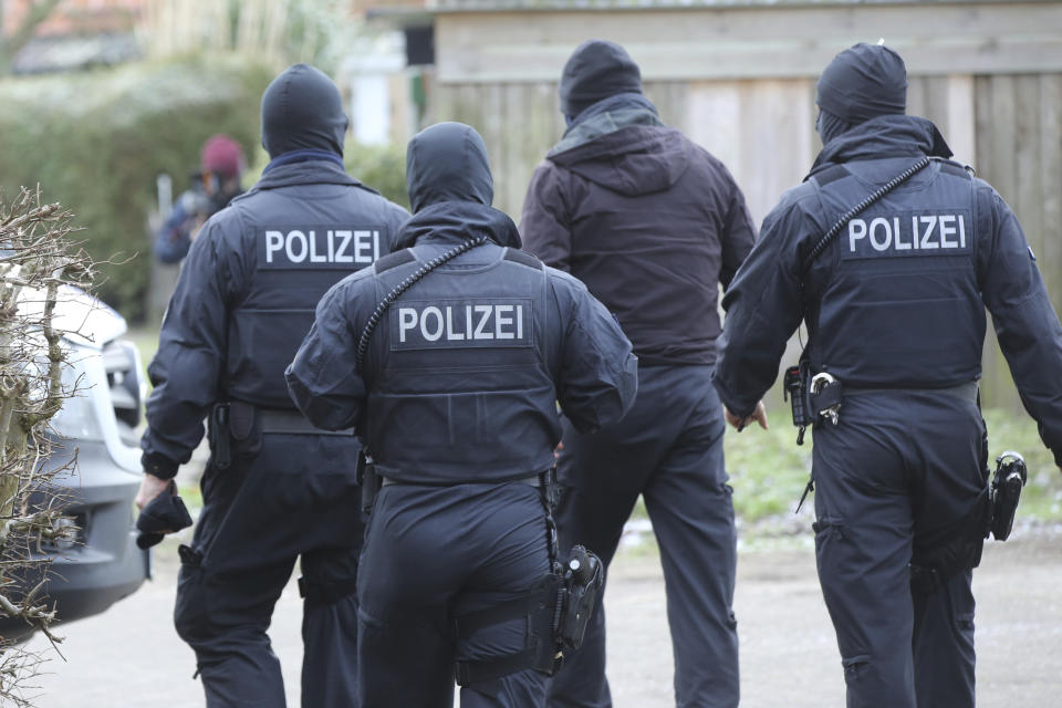 Police officer in front of at building during a raid in the village Meldorf, Germany, Jan. 30, 2019. German authorities arrested three suspected Islamic extremist Iraqi men in the norther German costal region, on allegations they were planning a bombing. (Bodo Marks/dpa via AP)