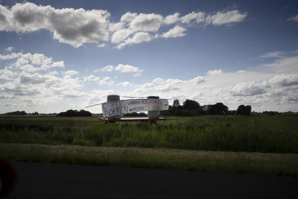 FILE- A sign reads "Number Are Changed, Farmers Get Screwed" along the motorway near Drachten, northern Netherlands, Monday, July 4, 2022. Dutch farmers angry at government plans to slash emissions used tractors and trucks Monday to blockade supermarket distribution centers, the latest actions in a summer of discontent in the country's lucrative agricultural sector. (AP Photo/Peter Dejong, File)