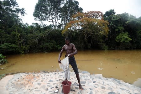 A man washes his clothes in a river polluted by gold mining waste in Nsuaem district