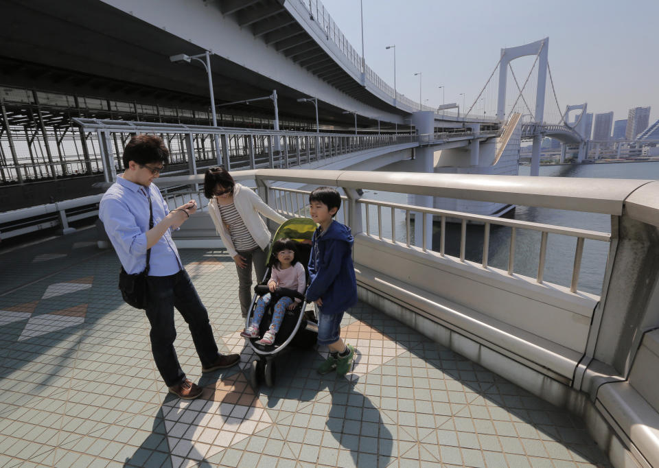 In this May 5, 2013 photo, a father takes a photo of his family on the walkway of the Rainbow Bridge in Tokyo. The walk is just over one mile (1.7 kilometers) including the 918-meter-long (just over half a mile) single-span suspension bridge and takes less than an hour one way. A walk on the north side of the bridge provides the panoramic view of Tokyo’s skyline. (AP Photo/Itsuo Inouye)